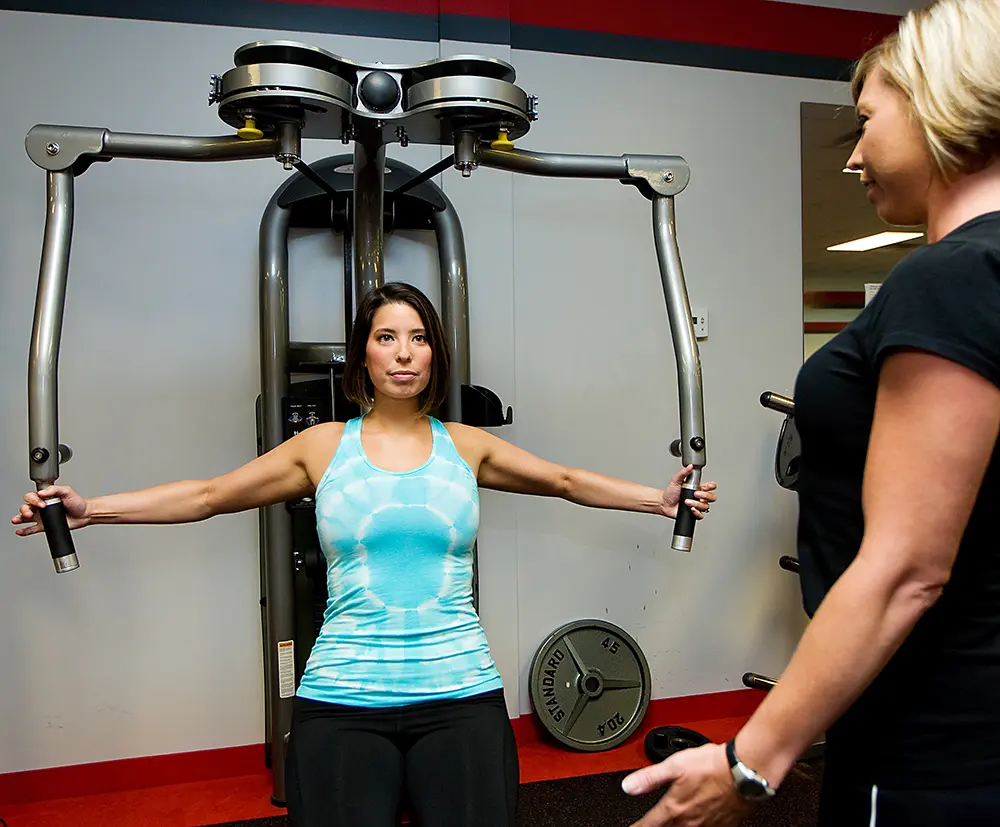 Personal trainer helping client with equipment